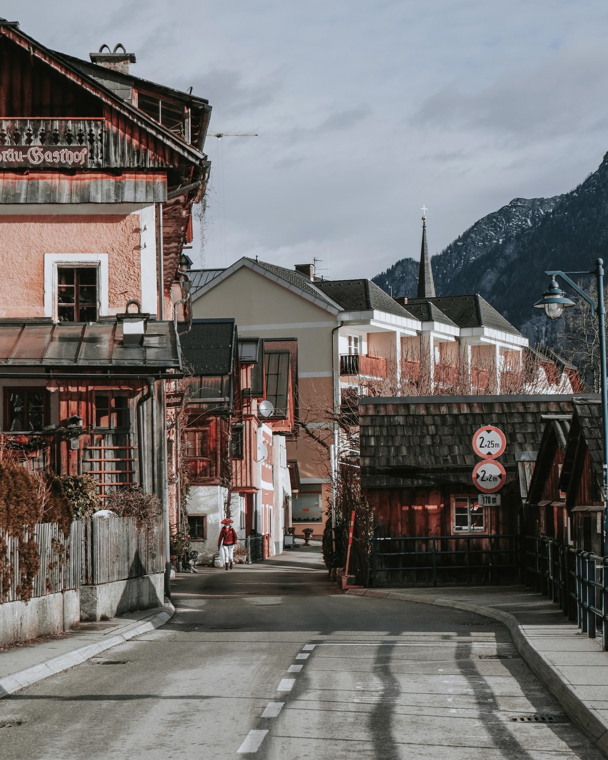 Österreichische Wohnstraße mit Häusern, Bergkulisse und Kirchturm